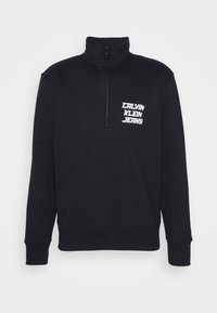 Sweat-shirt noir à fermeture quart-zip avec col montant, poignets et ourlet côtelés, et logo blanc "Calvin Klein Jeans" sur le côté gauche de la poitrine.