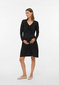 Robe de maternité noire à manches longues, décolleté en V, détail de fronces à l'avant et jupe ample ; fabriquée en tissu doux et extensible.