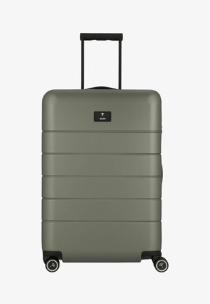 Zielona twarda walizka o matowym wykończeniu, poziomych rowkach, chowanym czarnym uchwycie i obrotowych kołach dla łatwej mobilności.