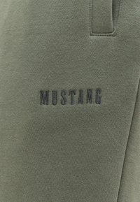 Zielona bluza z haftem "MUSTANG" w ciemnoniebieskim kolorze. Miękka tekstura materiału, prosty krój, okrągły dekolt i subtelne szwy.