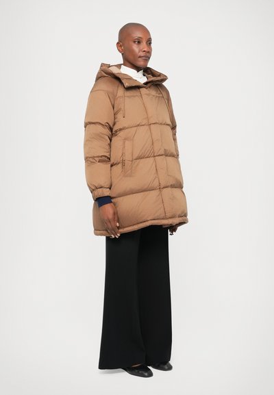 Casaco puffer castanho acolchoado com capucho, apresentando um fecho na frente, dois bolsos laterais e punhos elásticos, combinado com calças largas pretas.