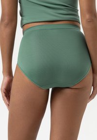 High-waisted, groene naadloze ondergoed gemaakt van zachte stof, met een gladde textuur en een elastische tailleband zonder zichtbare naden.