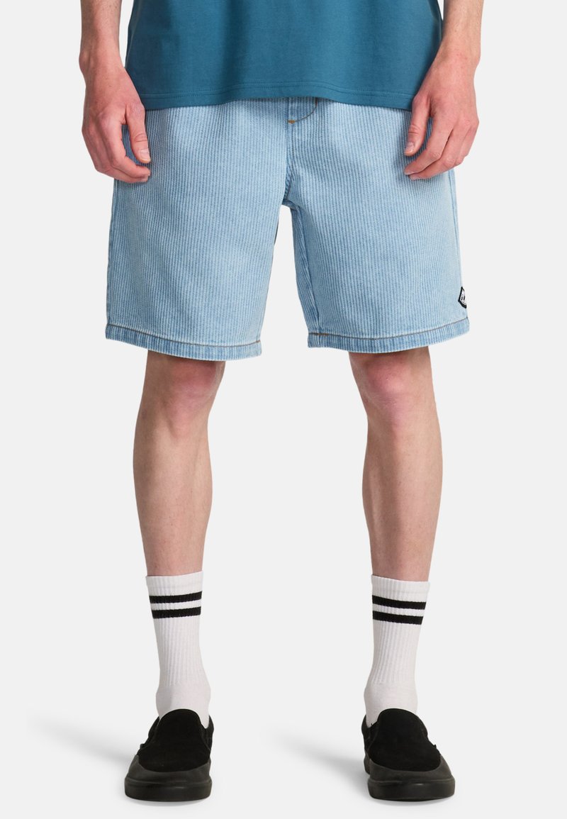 Jasnoniebieskie sztruksowe szorty w pionowe paski, długość ponad kolano, z podwiniętym brzegiem i małą czarną naszywką z logo po boku.