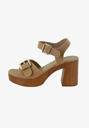 Sandales à plateforme beiges avec un talon bloc en bois, dotées de deux brides réglables avec des boucles dorées et une finition en cuir lisse.