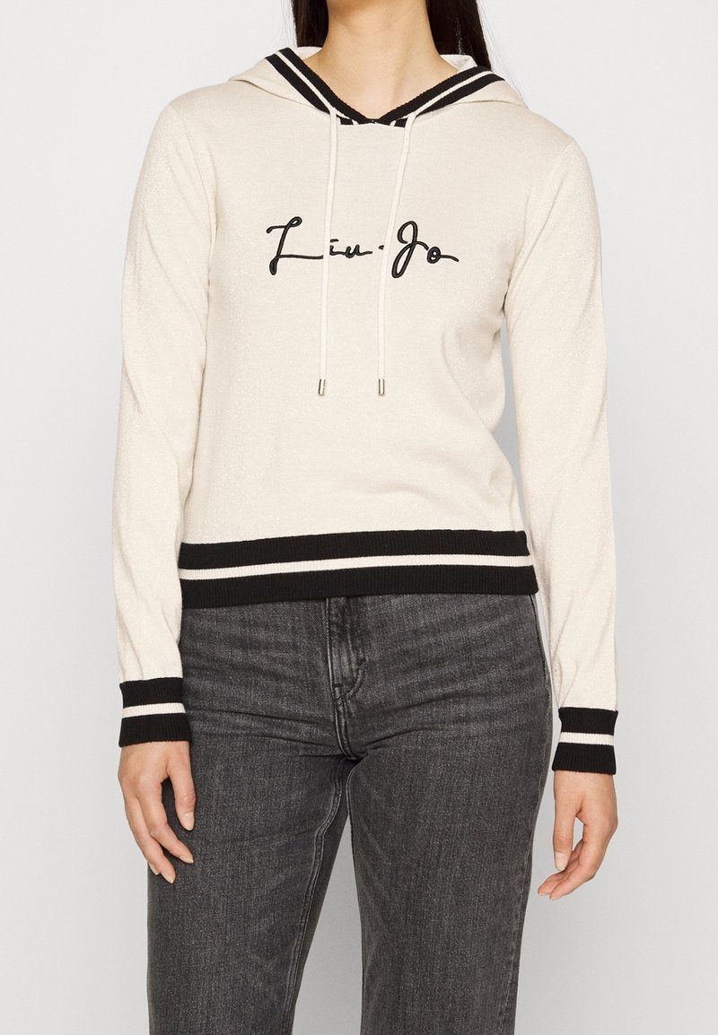 Sweat à capuche couleur crème avec accents noirs, doté d'un cordon de serrage, de poignets et d'un ourlet inférieur côtelés, avec le texte "Liu Jo" en cursive à l'avant.