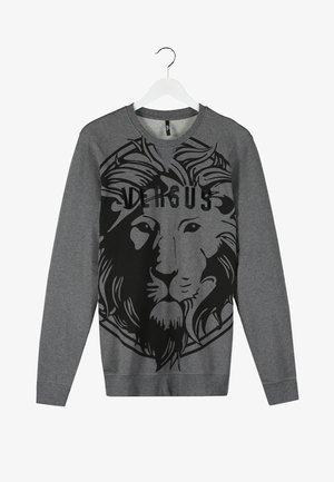 Czarna skórzana kurtka typu bomber, szara bluza z grafiką lwa, czarne dżinsy o dopasowanym kroju oraz wypolerowane czarne buty.