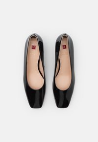 Černé lakované lodičky na vysokém podpatku s hranatou špičkou, hladkým povrchem a béžovými vložkami, s jemným brandingem na vložce.