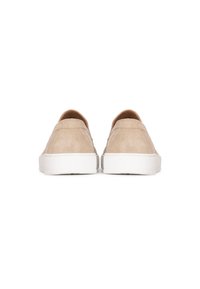 Zapatos de ante beige tipo slip-on con una textura suave, tacón redondeado y suelas de goma blanca. Diseño minimalista sin hardware visible.