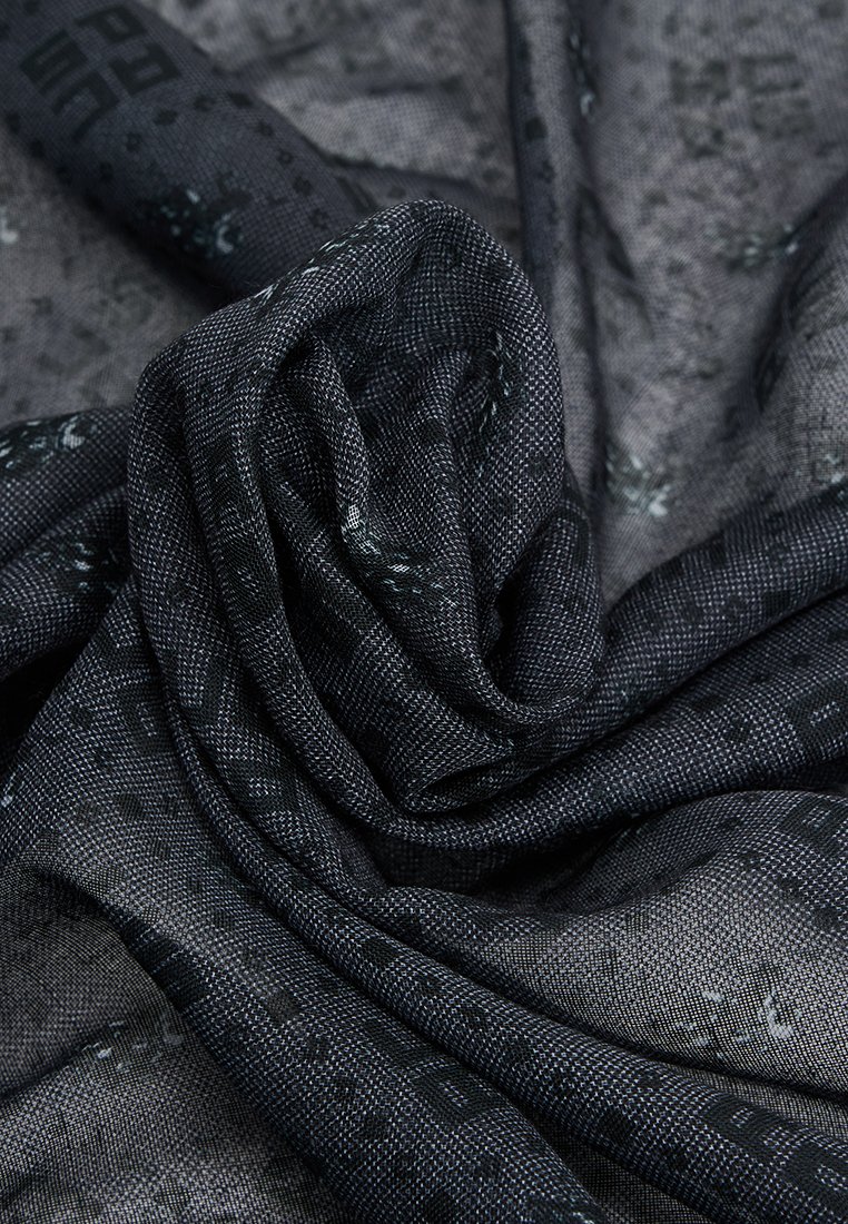 Czarny tkany szalik o teksturowanym wykończeniu, z subtelnymi wzorami geometrycznymi i miękkim, lekkim materiałem. Posiada pomarszczony, luźny wygląd.