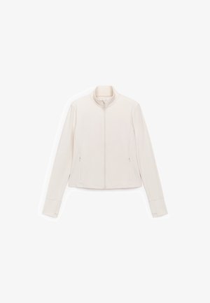 Light beige jacket with a stand-up collar, full zipper, and long sleeves. Features two side zip pockets and a smooth, soft texture.