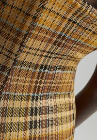 Abito in maglia con un motivo plaid marrone, giallo e blu. La texture appare liscia con una forma aderente e un colletto a contrasto.