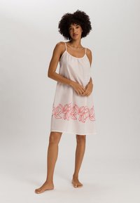 Vestido blanco sin mangas con un corte holgado, decorado con bordados florales en color coral en el dobladillo. Tela ligera y transpirable con una textura suave.