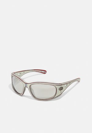 Ochelari de soare cu un cadru transparent, având o linie de accent roșie, lentile gri degradé și decupaje distincte pe tâmple.