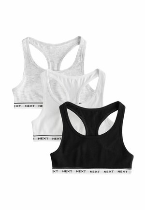 Tres sujetadores deportivos con espalda racer en negro, blanco y gris claro con bandas elásticas etiquetadas con "NEXT" en la parte inferior.