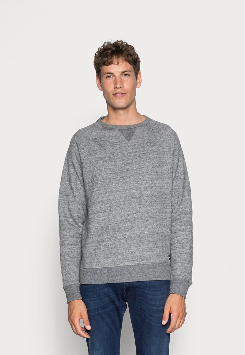 Grijze sweatshirt met een gestructureerd oppervlak, ronde halslijn en ribgebreide manchetten. Gecombineerd met blauwe jeans met een casual pasvorm.
