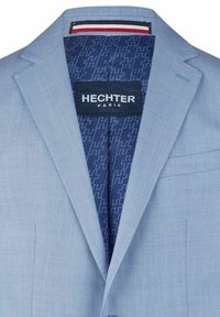 Hellblaues Sakko mit glatter Textur. Die Innenseite ist mit einem marineblauen Futter mit geometrischem Muster versehen und trägt ein Etikett mit der Aufschrift "HECHTER PARIS."