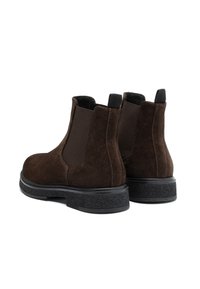 Botas de tobillo de ante marrón con paneles laterales elásticos, suelas texturizadas en negro y tiradores. Acabado suave con punta redondeada y estructura sólida.