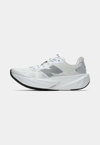 Baskets de course blanches avec une tige texturée, des accents réflecteurs, un logo "N" bien en évidence, une semelle épaisse et rembourrée, et une semelle extérieure noire.