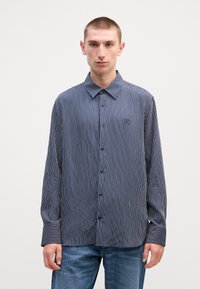 Μπλουζάκι με κουμπιά σε ναυτικό σχέδιο, με κολάρο, χαρακτηρισμένο από κατακόρυφες λευκές και μπλε ρίγες και κεντητό λογότυπο στο στήθος. Ύφασμα από μείγμα βαμβακιού.