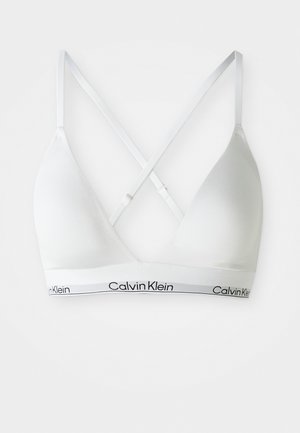 Vit triangel-bh med korslagda justerbara band och Calvin Klein-logotyp på den elastiska remmen i botten.