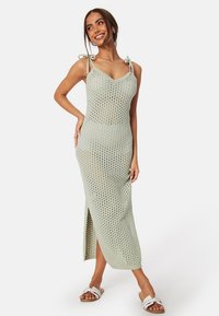 Abito maxi in maglia verde chiaro con scollo a V, motivo ad arazzo e spacco laterale, dotato di spalline regolabili e silhouette aderente.