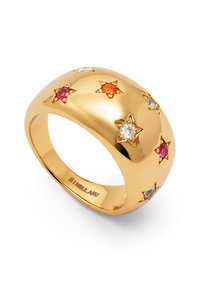 Anillo de oro con una superficie lisa y redondeada, que presenta engastes en forma de estrella con piedras rosas, naranjas, claras y azules distribuidas a su alrededor.