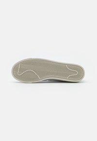 Suela de zapato de goma con un patrón texturizado en espiga. Bordes suaves, color beige claro y sección de la punta ligeramente curvada para un diseño ergonómico.