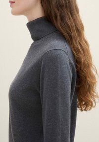 Grauer Strickrollkragenpullover mit geripptem Kragen, figurbetontem Schnitt und langen Ärmeln, der eine glatte Textur und eine schlichte Bauweise präsentiert.