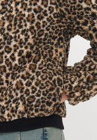 Sweatshirt med leopardmønster i falsk pels med myk tekstur, mørke ribbede mansjetter og hem. Designet for komfort med en avslappet passform.