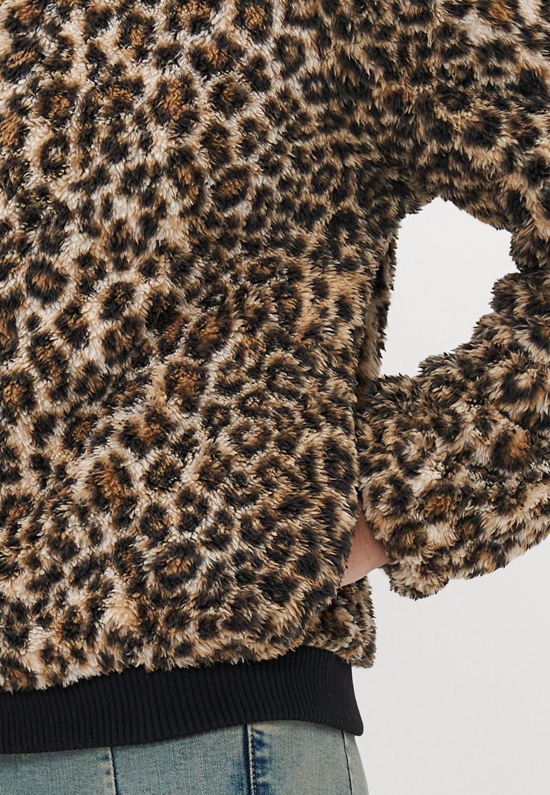 Sweatshirt en fausse fourrure imprimé léopard avec une texture douce, des poignets et un ourlet côtelés foncés. Conçu pour le confort avec une coupe décontractée.