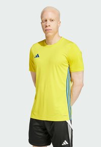 Geel sport T-shirt met blauwe strepen, ronde halslijn, korte mouwen en ademende stof, gecombineerd met zwarte sportshorts.