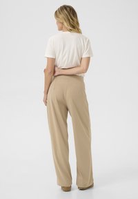 Beige wide-leg trousers with a smooth texture, featuring a high waistband and pleats, paired with a plain white short-sleeve top.