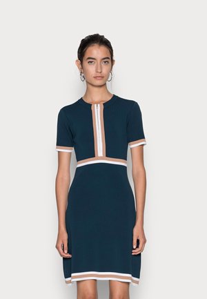 Vestido de punto navy con mangas cortas, presenta un cierre frontal y rayas en beige y blanco en el escote y el dobladillo. Cintura ajustada.