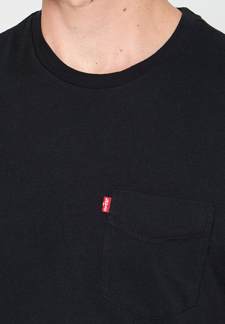 Zwarte katoenen T-shirt met een ronde halslijn en korte mouwen. Beschikt over een borstzak met een rode Levi's logo-label. Zachte textuur, eenvoudig ontwerp.
