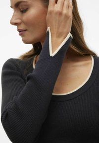 Maglione a coste di un blu navy scuro con collo e rifiniture crema, caratterizzato da un distintivo dettaglio a forma di V ai polsini.