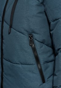 Teal pufferjack met een diagonale quiltpatroon, zwarte ritszak en een trekkoord in de capuchon voor verstelbare bedekking.