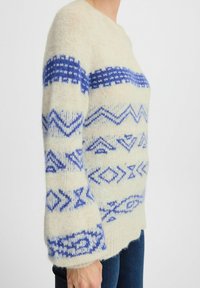 Pulover crem cu modele geometrice albastre, material texturat, decolteu rotund și mâneci largi. Purtați-l cu blugi de culoare albastru închis.