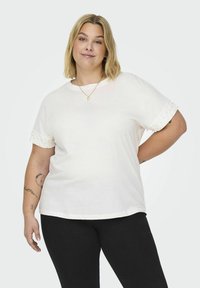 Hvid bomulds t-shirt med korte ærmer, med struktureret stof ved manchetterne. Løs pasform med en rund udskæring. Enkelt design, ingen mønstre.