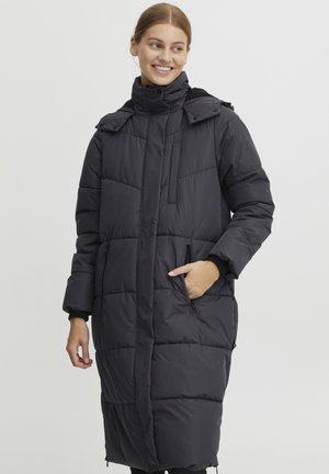 Long, padded puffer coat in black with side pockets, high collar, and buttoned shoulder details. Smooth texture and knee-length design.