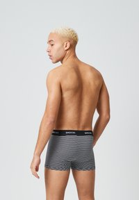 Zwart-wit gestreepte boxershorts met een zwarte tailleband met het label "SNOCKS," met een strakke pasvorm en een zachte stof textuur.