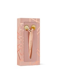 Różowe złote wałek do twarzy z dwoma żółtawymi głowicami kryształowymi, zapakowany w geometryczne różowe pudełko z przezroczystym okienkiem i oznaczeniem marki.