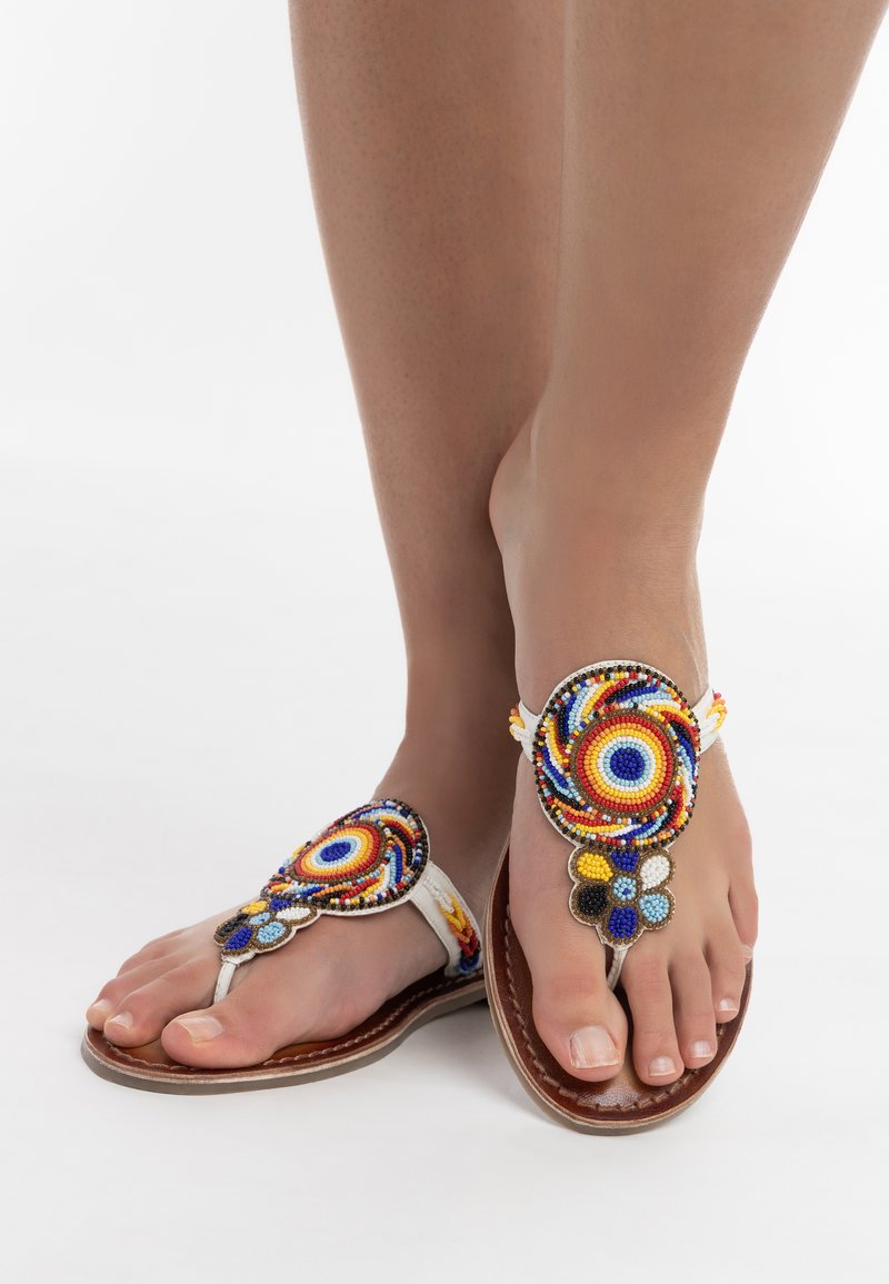 Perleflip-flops med en hvid rem, der har farverige cirkulære mønstre, brun sål og dekorative detaljer i blå, gul og sort.