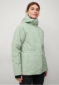 Lys grøn vandtæt jakke med hætte, lynlåslukning, justerbar talje og sidelommer. Glat tekstur og minimalistisk design.
