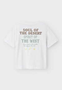 Valge puuvillane T-särk, millel on prinditud tekst pruunis, rohelises ja kollases ning tagaküljel kõrbe teemaga graafika. Lühikesed varrukad, ümar kaeluse disain.