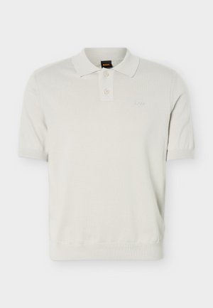 Polo à manches courtes de couleur blanc cassé avec poignets et ourlet côtelés, deux boutons et petit logo "BOSS" embossé sur le côté gauche de la poitrine.