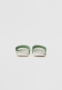 Gröna stövlar i sandalsstil med en slät, flexibel design, rund tå och en vadderad sula för komfort.