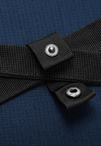 Tissu texturé bleu marine avec des sangles noires et des fermoirs métalliques. Les sangles présentent une texture lisse et de grandes fermetures à pression circulaires.