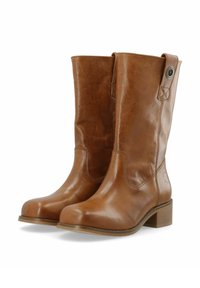 Pruunid nahast põlvikud, millel on sile viimistlus, plokk-kand ja dekoratiivne õmblus. Omab külgsuunas nupuga aktsenti.