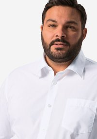 Camisa blanca de corte clásico con cuello, fabricada en tejido texturizado y con un bolsillo en el pecho izquierdo; cuenta con cierre de botones estándar.