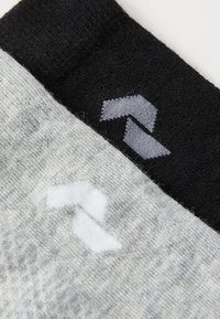 Calcetines de algodón en gris y negro, con un patrón sutil. Cada calcetín tiene un logo en forma de chevron en colores contrastantes en el tobillo.